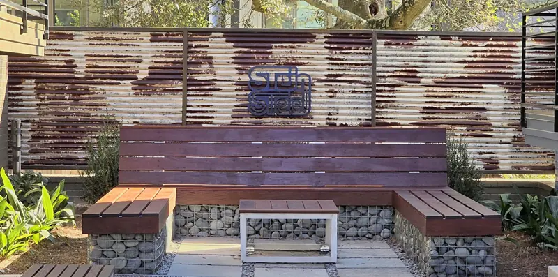 Courtyard seating area with custom hardwood benches and table on stone-filled gabion bases
