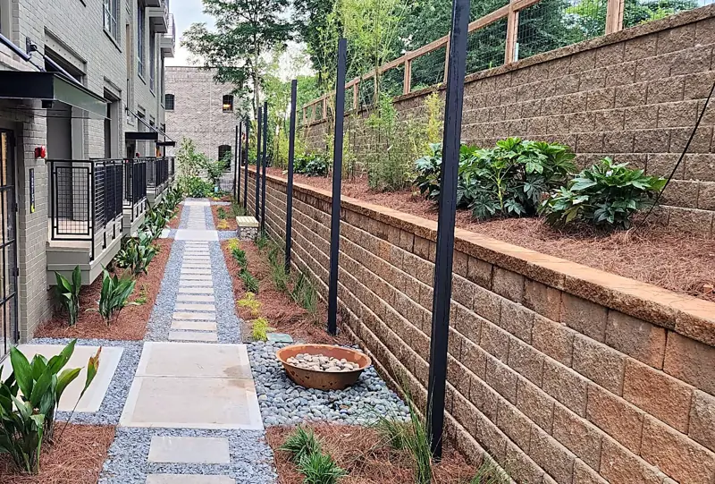 Stepping-stone walkway with gravel, planting beds and a block retaining wall